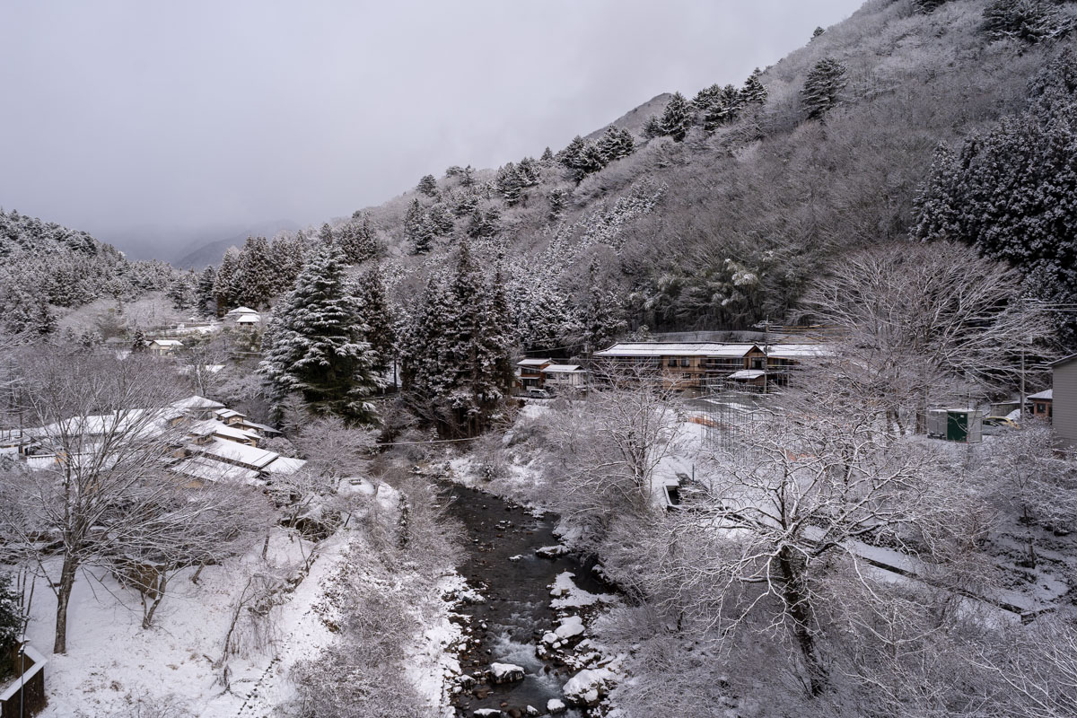 雪に包まれた四万温泉・温泉口エリアの山と四万川
